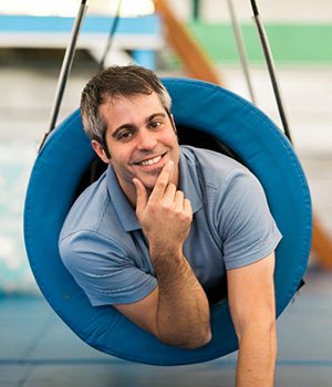 Occupational Therapist Andrew Klein inside a tunnel swing in the sensory gym