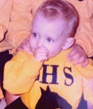 Brittni Winslow, executive director of Emerge Pediatric Therapy, as a infant, wearing a yellow sweat shirt while sucking on her thumb