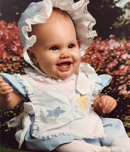 Occupational Therapist Jacklyn as a infant in a white bonnet