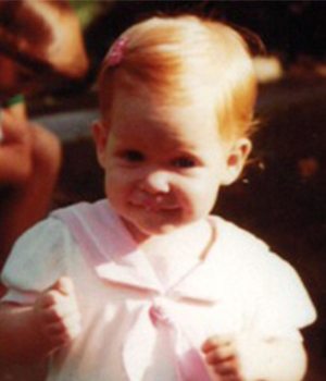 Speech Language Pathologist and Clinical Director of Speech Language Therapy Kelly as a infant girl wearing a pink and white dress