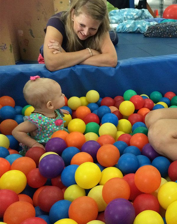 Niña pequeña en piscina de bolas para juegos sensoriales en gimnasio sensorial para terapia ocupacional