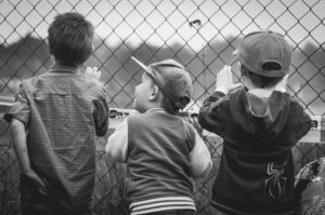 three boys watching a baseball game