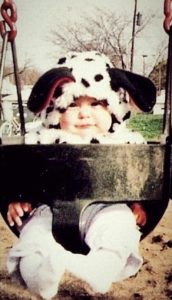 Alexa Whitt, occupational therapist as a baby dressed in a puppy outfit seated in a swing