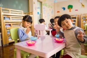 one girl and two boys eating at table together