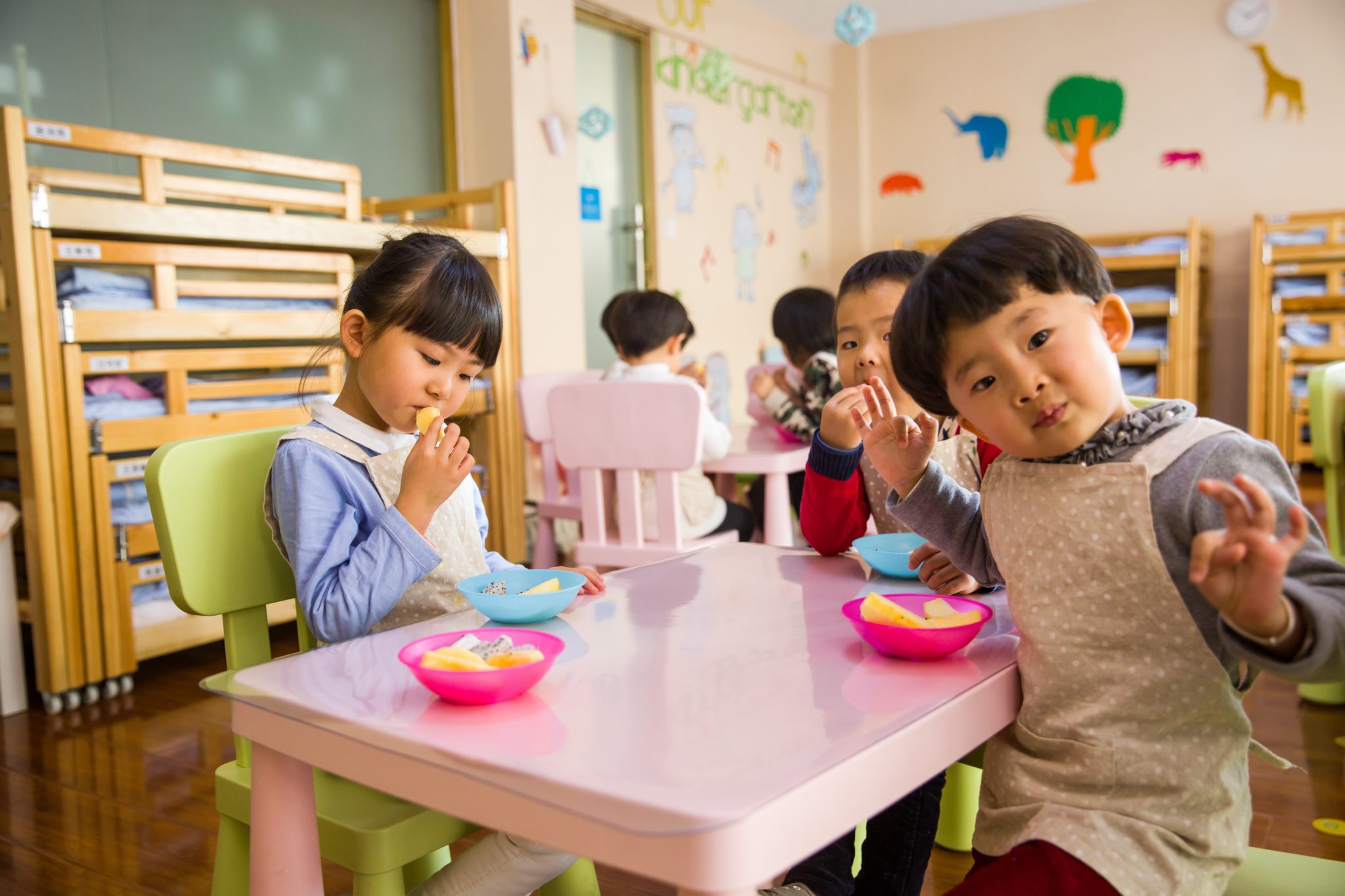 una niña y dos niños comiendo juntos en la mesa
