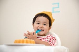 baby sitting in a high chair celebrating his second birthday
