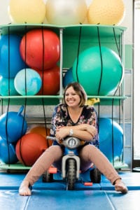 Occupational Therapist Nicole sitting on a tricycle in the sensory gym