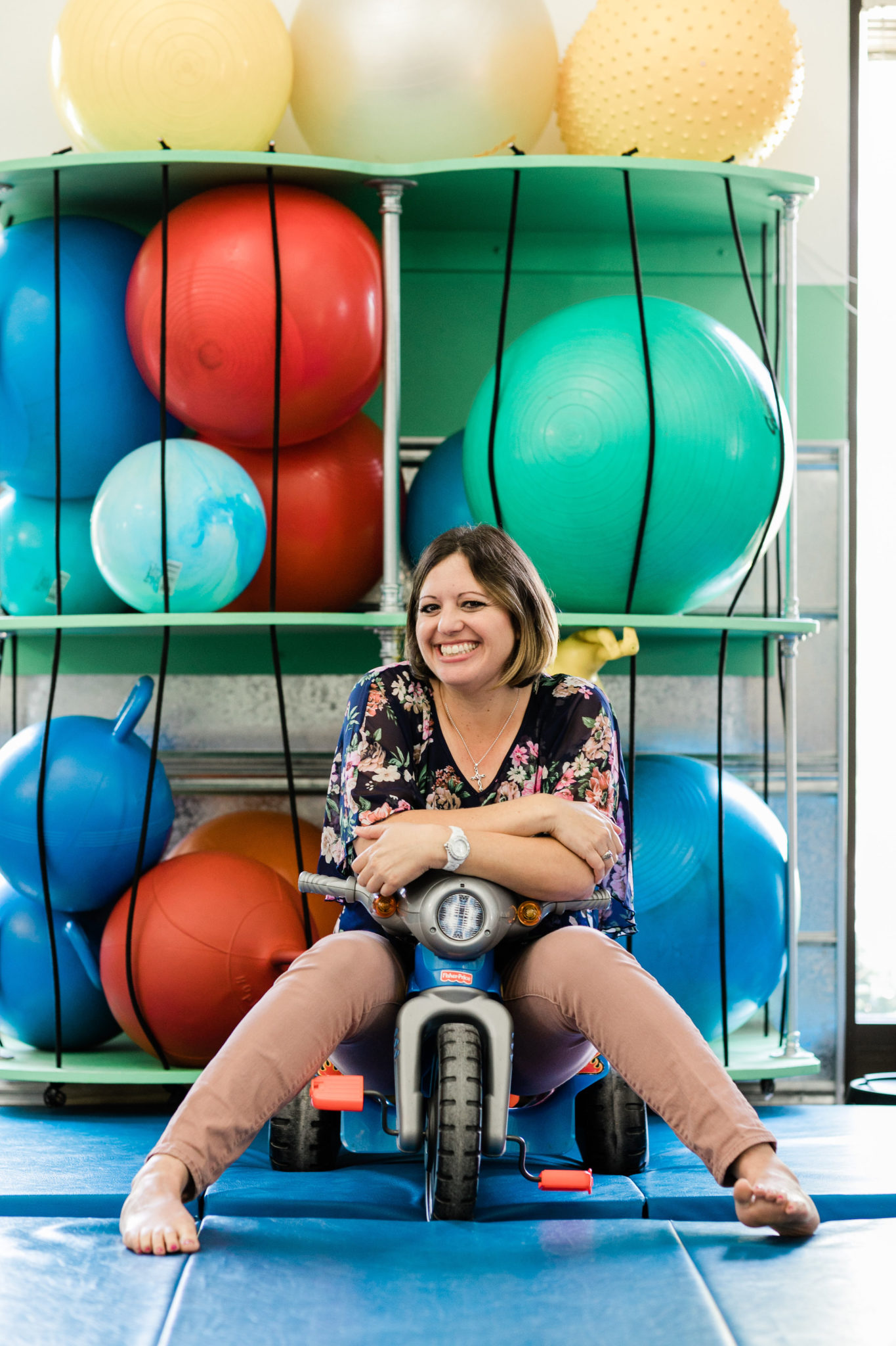 Occupational Therapist Nicole sitting on a tricycle in the sensory gym
