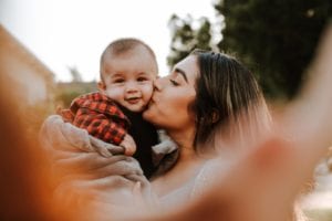 mom kissing infant baby on the cheek