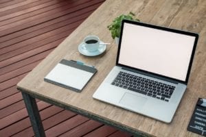 Apple MacBook with Wacom tablet next to coffee cup on a table