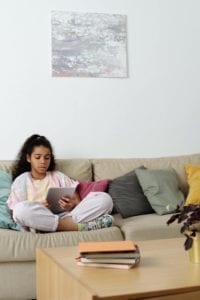 girl sitting on the sofa reading on her tablet