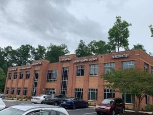 Two story brick building with large windows. Large white letters go across the top of the building announcing the names of the businesses inside, including Emerge Pediatric Therapy