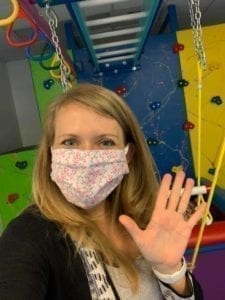 Occupational Therapist Brittni wearing PPE face mask waving hand in Sensory Gym