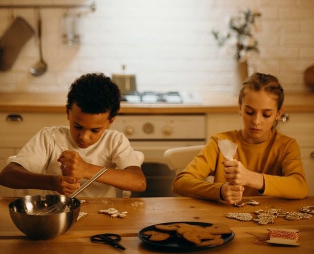 boy and girl piping icing onto cookies