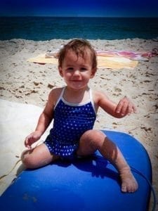 Speech Language Pathologist Danielle as an infant wearing a blue swimsuit sitting on a blue float at the beach