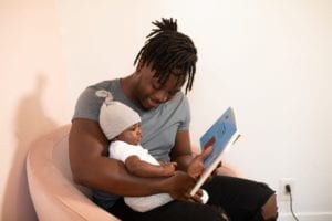 young father reading book to infant son