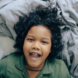 Young boy on bed facing up with his mouth open