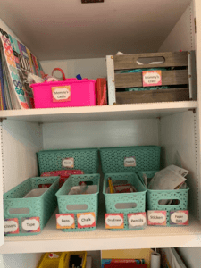 up close image of colorful blue and pink bins, labeled neatly with various school supplies