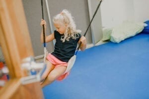 Girl swinging on a frog swing in the small sensory gym