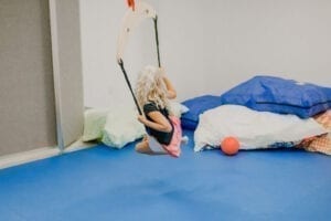 Girl swinging on a frog swing in the small sensory gym