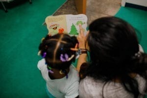 Speech-language pathologists reading with a young girl