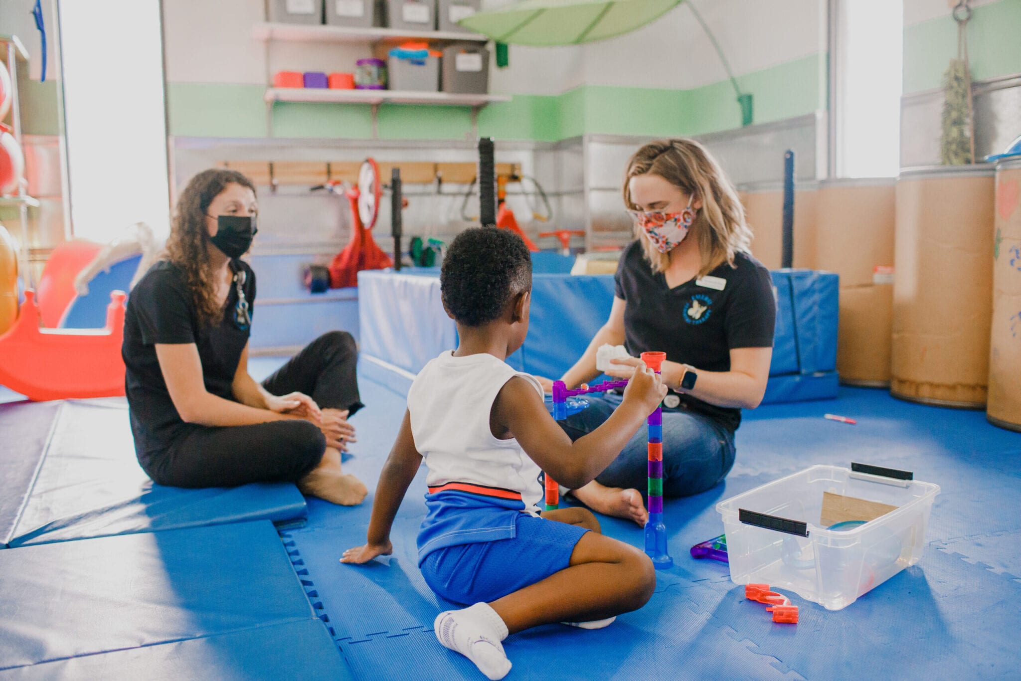 Dos terapeutas femeninas que trabajan con un niño en un gimnasio sensorial