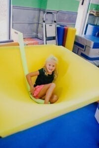 Young girl sitting in the middle of a cloud swing in the Sensory Gym
