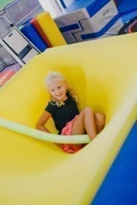 Young girl sitting in the middle of a cloud swing in the Sensory Gym