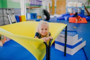 Young girl sitting in the middle of a cloud swing in the Sensory Gym