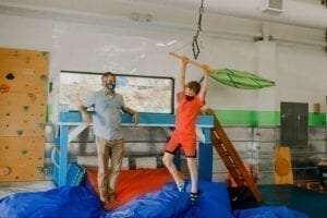 Boy swinging from a trapeze swing in the Sensory Gym