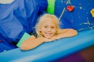 Young girl smiling from the foam pit in the Sensory Gym