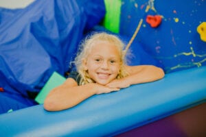 Young girl smiling from the foam pit in the Sensory Gym