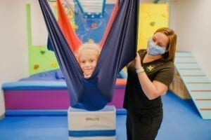 Young girl in a cloud swing with an occupational therapist