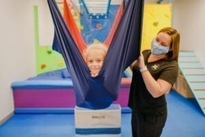 Young girl in a cloud swing with an occupational therapist