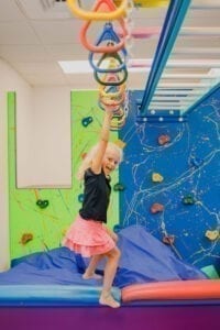 Young girl swinging on the monkey bars in the Sensory Gym