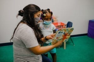 Speech-language pathologists reading with a young girl