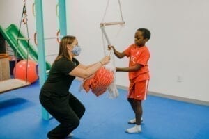 Boy and Occupational Therapist putting Elmo into a net swing