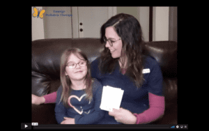 White, brunette, female therapist in glasses sits on a leather sofa with her daughter