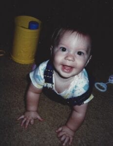 baby smiling at the camera while crawling on hands and knees