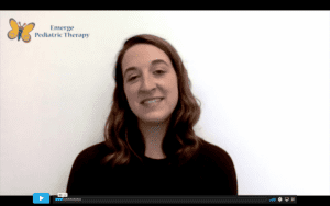 white female therapist with brown hair smiles at the camera sitting infant of a white background