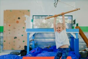 Photo of a happy little girl hanging from a therapy bar