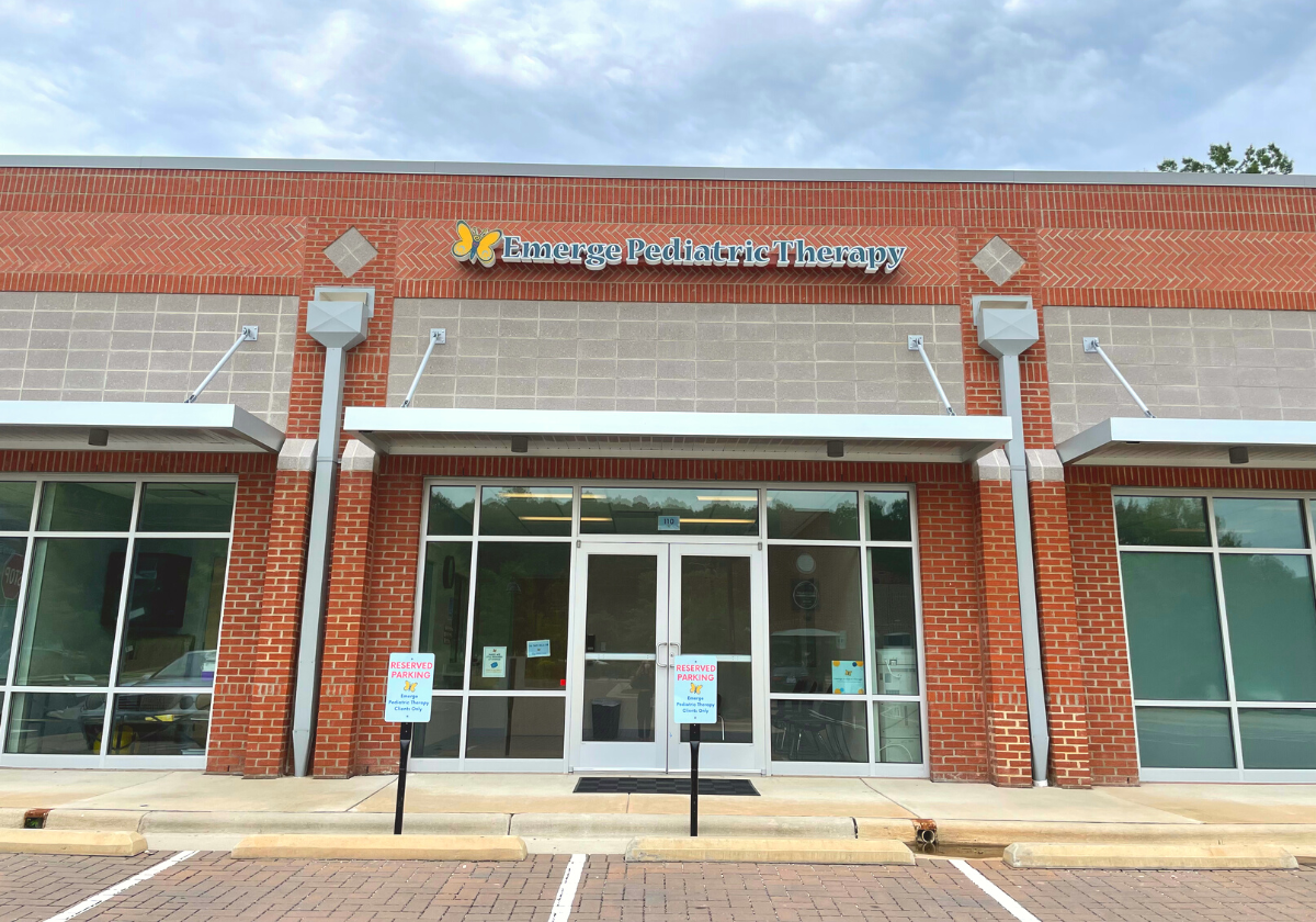 Two story brick building with large windows. Large white letters go across the top of the building announcing the names of the businesses inside, including Emerge Pediatric Therapy